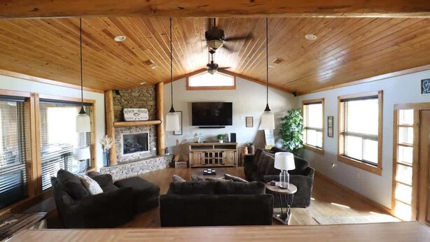 A spacious living room with a fireplace, wooden ceiling, and large windows. - Spacious Retreat on Caddo River, Amity (Amity)