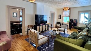 Un salón amplio con un televisor grande, asientos cómodos y un techo con un diseño único.