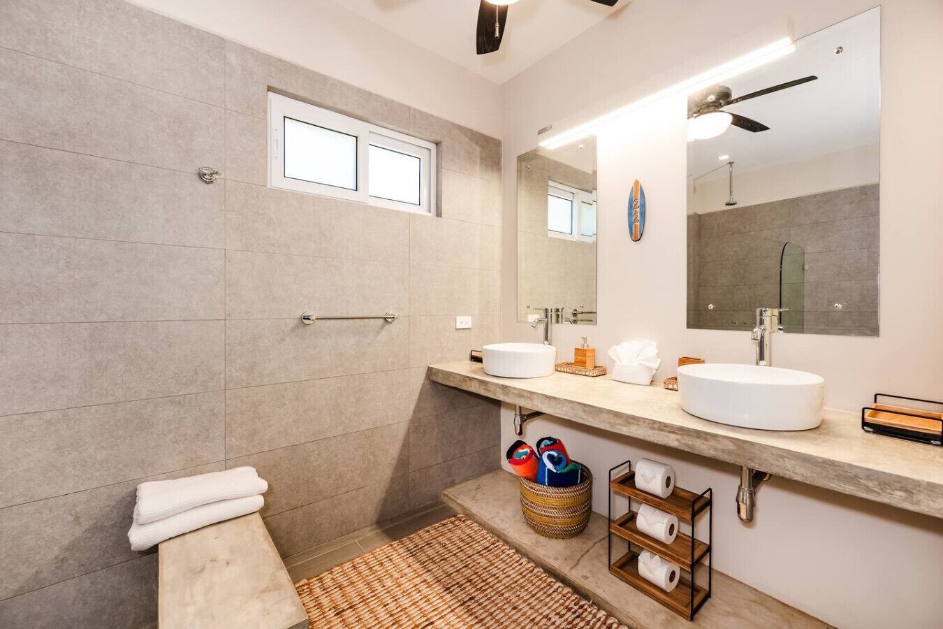 A modern bathroom with two sinks, a large mirror, and a shower area.