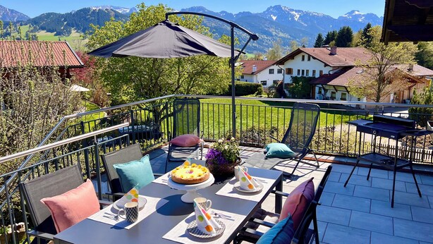 A terrace with a table set for dining, a chair, and a potted plant.