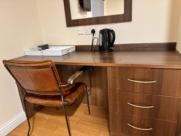 A compact workspace with a wooden desk, a leather chair, and a coffee maker. - The Bell and Bottle (Slough)