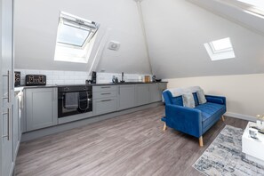 Cozy living space with a kitchen area, featuring an oven and microwave, and a comfortable sofa.