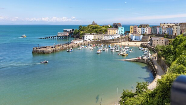 A coastal town with a marina, colorful buildings, and a historic tower.