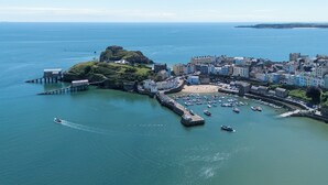 An aerial view of a coastal town with a pier, boats, and colorful buildings.