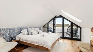 Un dormitorio con una cama de madera, vistas al exterior y un tragaluz.