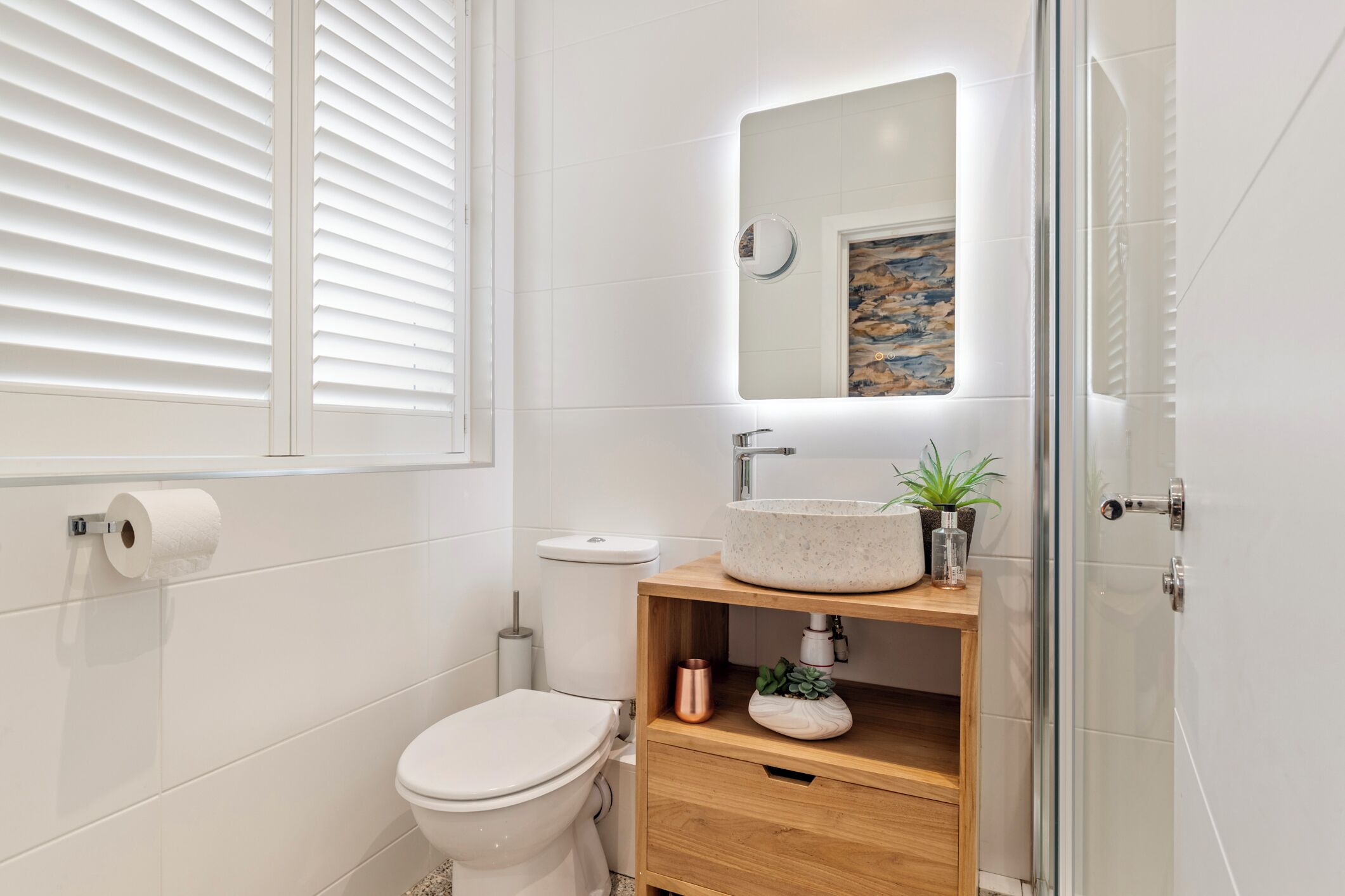 A modern bathroom with a toilet, sink, and mirror.