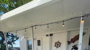 A covered outdoor patio with string lights, a table, chairs, and a decorative ship wheel. - The Newly Renovated  Couples  Retreat in Key Largo , Pool  beach , and Marina  (Key Largo)