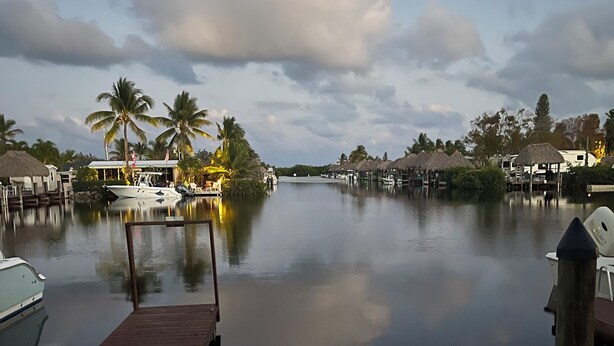 A calm waterfront area with a wooden dock, boats, and thatched-roof structures. - The Newly Renovated  Couples  Retreat in Key Largo , Pool  beach , and Marina  (Key Largo)
