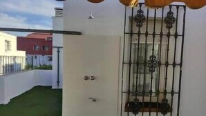 A white building with a metal gate and a window with decorative bars. - Plaza España Family House, amplia casa con parking gratuito en la calle, ideal para familias y grupo... (Seville)