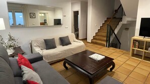 A living room with a sofa, a coffee table, a staircase, and a TV. - Plaza España Family House, amplia casa con parking gratuito en la calle, ideal para familias y grupo... (Seville)