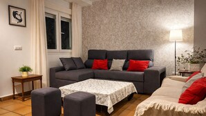 A cozy living room with a grey sofa, ottomans, a small table, and a lamp. - Plaza España Family House, amplia casa con parking gratuito en la calle, ideal para familias y grupo... (Seville)