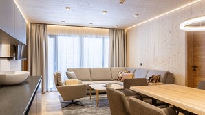 A modern living room with a sofa, chairs, a coffee table, and a wooden dining table. - Premium Suite With Private Sauna (Saalbach-Hinterglemm)