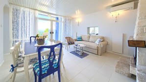 A living room with a dining area, a sofa, a chair, and a table with a vase of flowers. - Villa Sea Bound with Pool (Malinska)