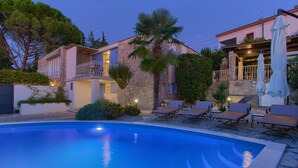 A pool area with lounge chairs, a stone building, and a palm tree. - Villa Sea Bound with Pool (Malinska)