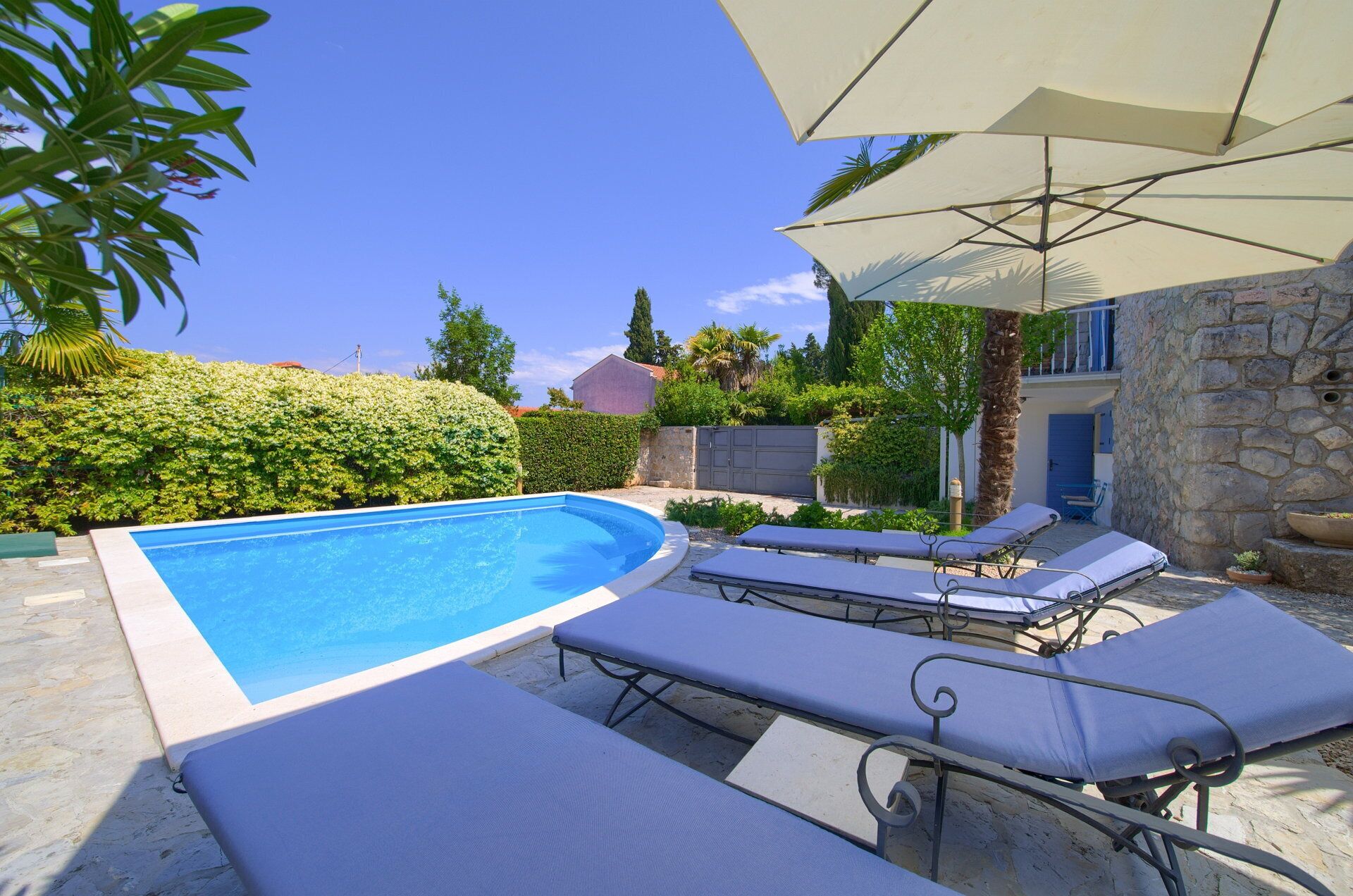 A swimming pool with lounge chairs and an umbrella.