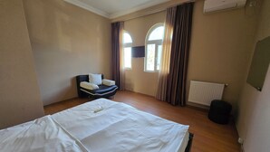 A hotel room with a large bed, a chair, a window with curtains, and an air conditioning unit. - Kale Park  (Batumi)
