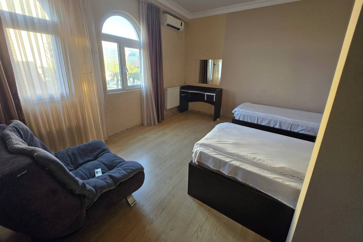 Ein Hotelzimmer mit Bett, Schreibtisch, Stuhl und einem fensterbepflanzten Fenster.