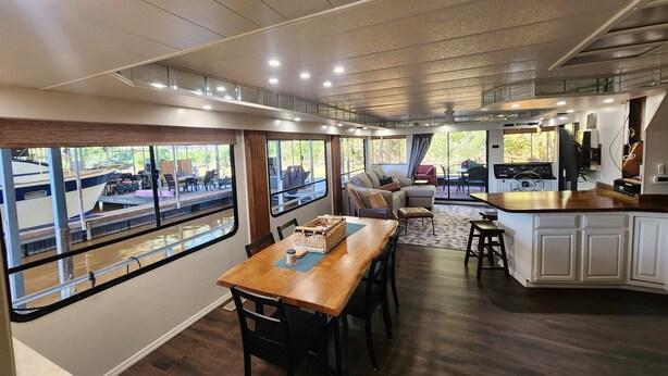 A modern interior with a dining area, kitchen, and large windows overlooking a dock. - Pier D Lite 4 bdrm Houseboat on River Downtown Knoxville - walk to Univ. of TN  (Knoxville)