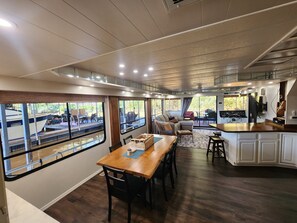 A modern interior with a dining area, kitchen, and large windows overlooking a dock.