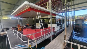 A boat with a covered deck, seating area, and a ladder. - Pier D Lite 4 bdrm Houseboat on River Downtown Knoxville - walk to Univ. of TN  (Knoxville)