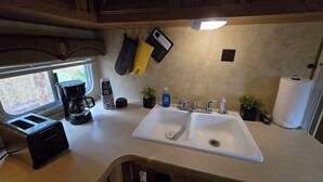 Een keuken met een dubbele spoelbak, een koffiezetapparaat en een raam.