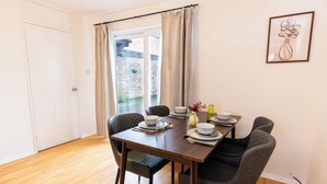 Comedor con una mesa de madera dispuesta para cuatro personas, rodeada de sillas oscuras.