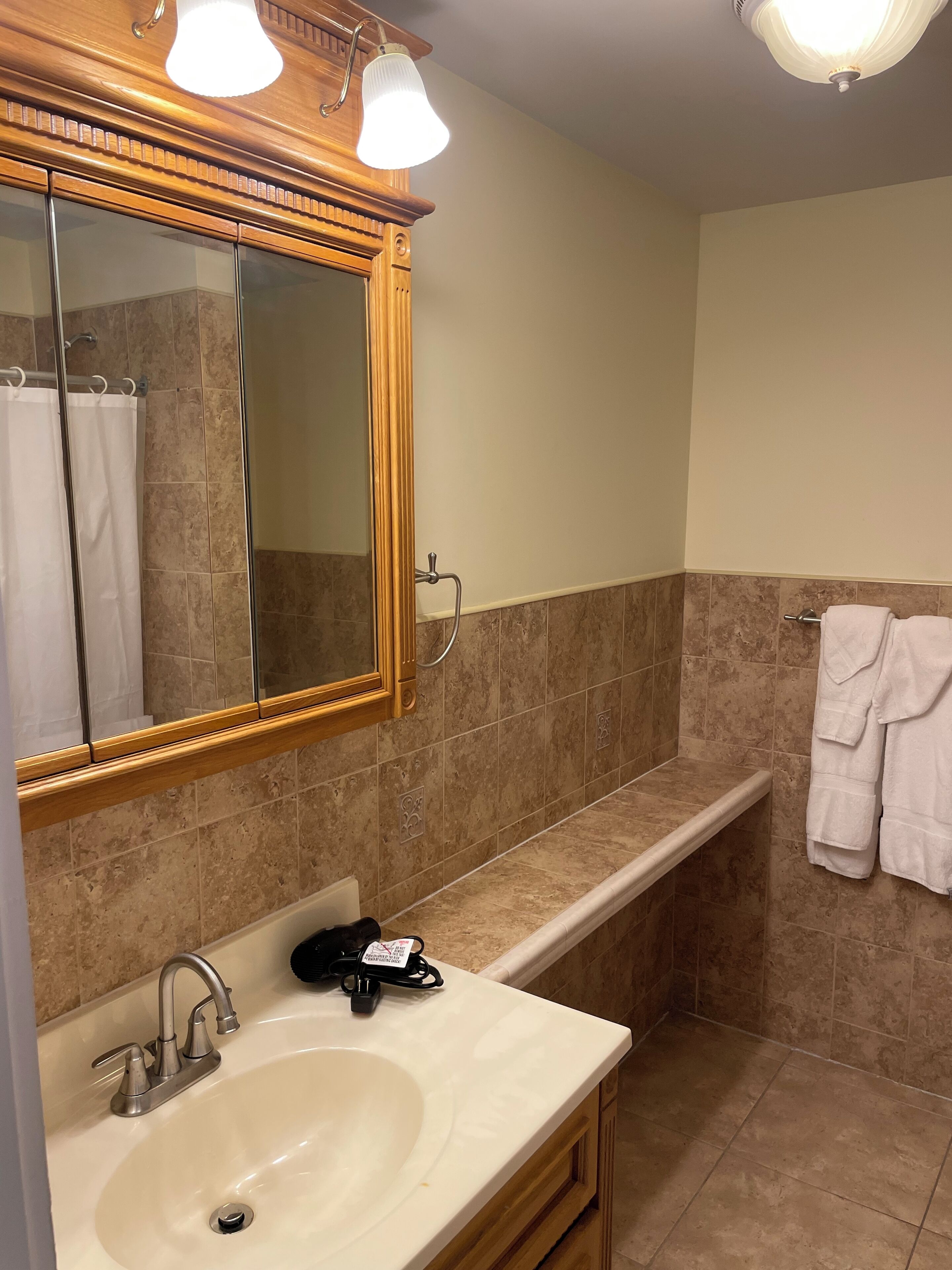 A bathroom with a large mirror, a sink, a towel rack, and a shower area.