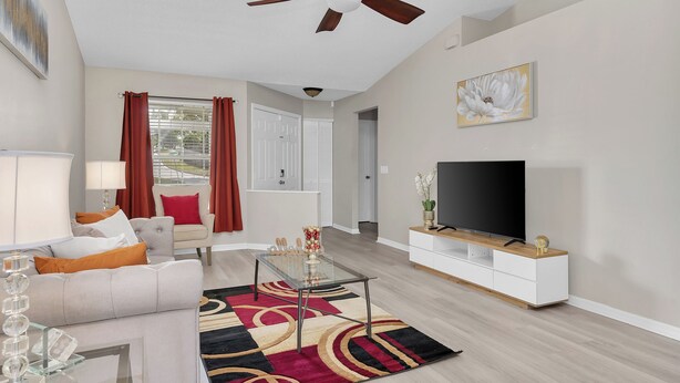 Een moderne woonkamer met een bank, salontafel, televisie en decoratieve accessoires.