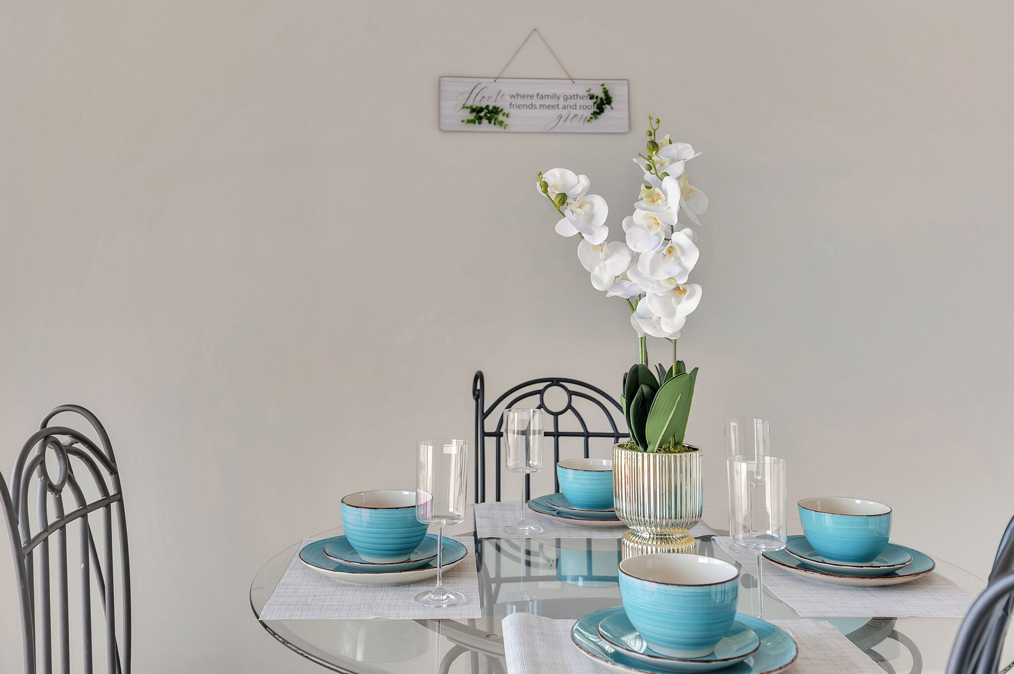 Ein Esstisch, gedeckt mit blau-weißen Tellern, Schalen und klaren Gläsern, mit einer Orchidee im Topf darauf.