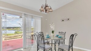 Een eetruimte met een tafel en stoelen, uitzicht op een meer door een schuifdeur en een hanglamp.
