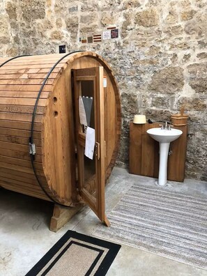 A wooden sauna with a door, a sink, and a stone wall in the background. - Albert's Glen Lovely King Studio walking distance to downtown (Galena)