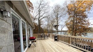 A wooden deck with a grill, outdoor seating, and a view of a lake. - Mountain Ferry Landing - Riverfront Access (Charles Town)