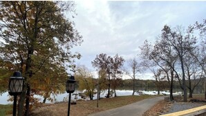A wooden deck with a railing overlooking a lake, surrounded by trees with autumn foliage. - Mountain Ferry Landing - Riverfront Access (Charles Town)