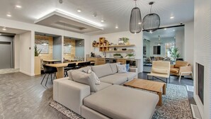 A modern living room with a sectional sofa, a wooden coffee table, and a dining area with a kitchen in the background. - LCF - Sugarhood - Sugar House- 3BR/2BA - CoWork + Gym - 2 Kings + Queen (Salt Lake City)