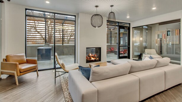 A modern living room with a fireplace, leather sofa, and a glass door leading to an outdoor area. - LCF - Sugarhood - Sugar House- 3BR/2BA - CoWork + Gym - 2 Kings + Queen (Salt Lake City)