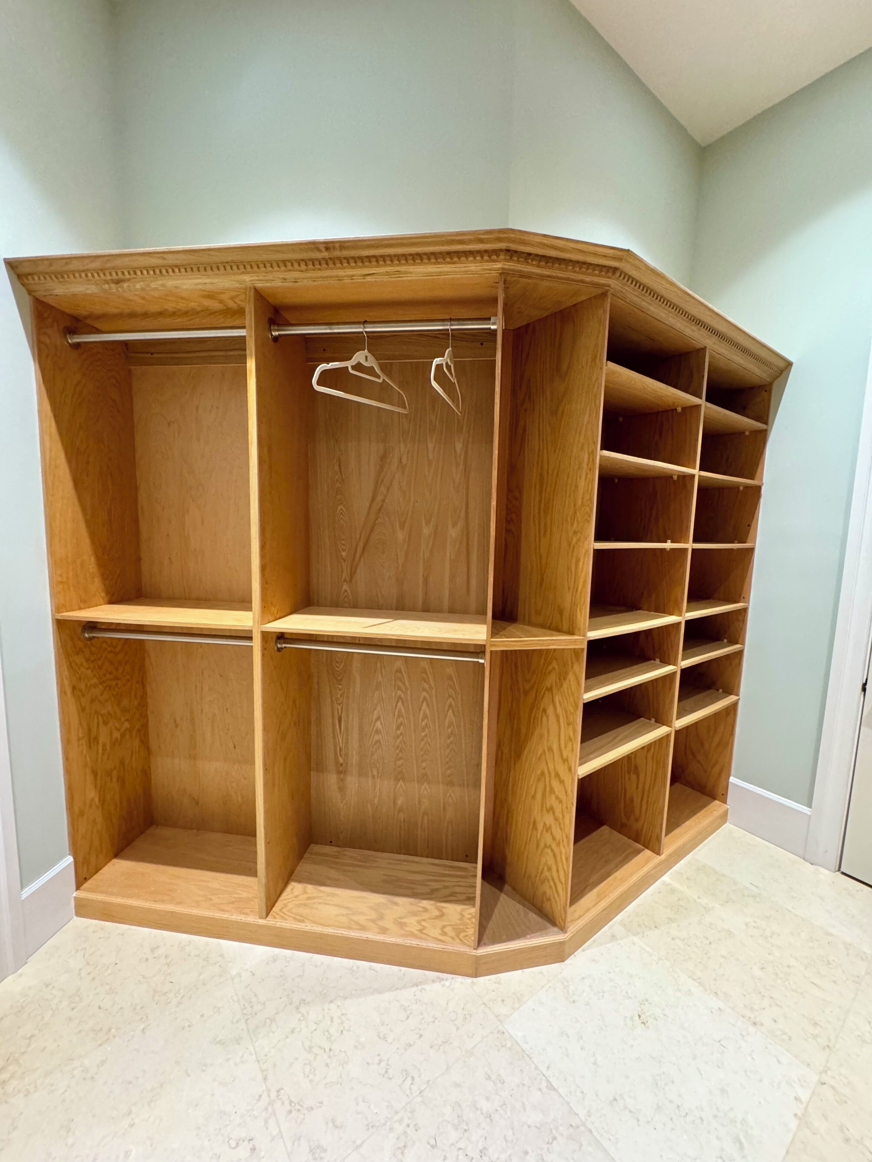 A corner closet with open shelves and hanging space.