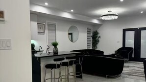 A modern kitchen with a black countertop, bar stools, and a large mirror. - new house. built in 2022

 (Stratford)