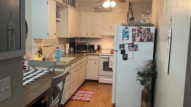 A kitchen with white cabinets, a microwave, a refrigerator, and a dining area with a wooden table and chairs. - Charming 2-bedroom house in delightful Jackson with AC, WiFi (Jackson)