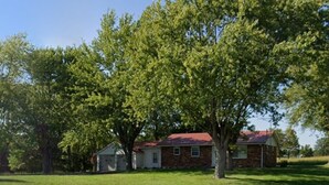 A single-story brick house with a red roof, surrounded by a well-maintained lawn and large trees. - Charming 2-bedroom house in delightful Jackson with AC, WiFi (Jackson)