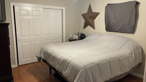 A bedroom with a bed, a ceiling fan, a star decoration, a door, and a window with a curtain. - Charming 2-bedroom house in delightful Jackson with AC, WiFi (Jackson)