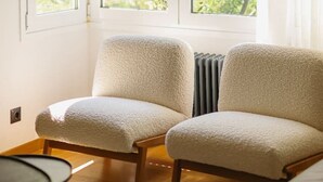 Une pièce avec deux fauteuils beiges, une petite table et un radiateur.
