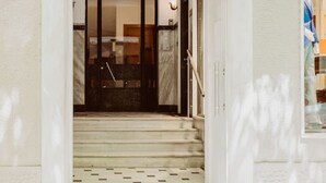 L’entrée d’un hôtel, avec un escalier en marbre menant à une porte en verre.