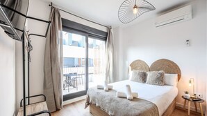 A hotel room with a bed, a balcony, a hanging light fixture, and an air conditioning unit. - Elegant Studio with Private Terrace by RentitUP (San Sebastián de los Reyes)