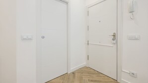 A hallway with two white doors, a light switch, and a telephone on the wall. - Urban Tranquility in Madrid with Modern Comforts (Madrid)