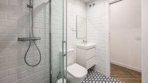 A modern bathroom with a glass shower enclosure, a white sink, and a toilet. - Urban Tranquility in Madrid with Modern Comforts (Madrid)