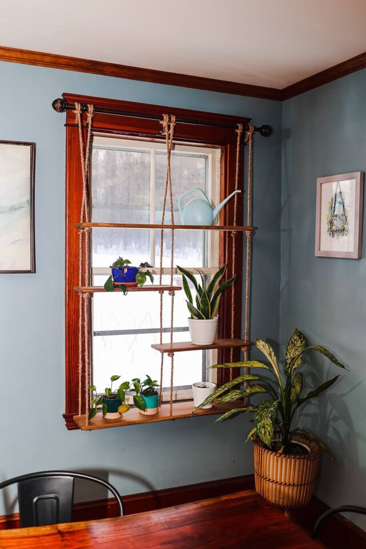 Une pièce avec un rebord de fenêtre en bois servant d’étagère, sur lequel sont posées des plantes, ainsi qu’une chaise et un pot de fleurs.