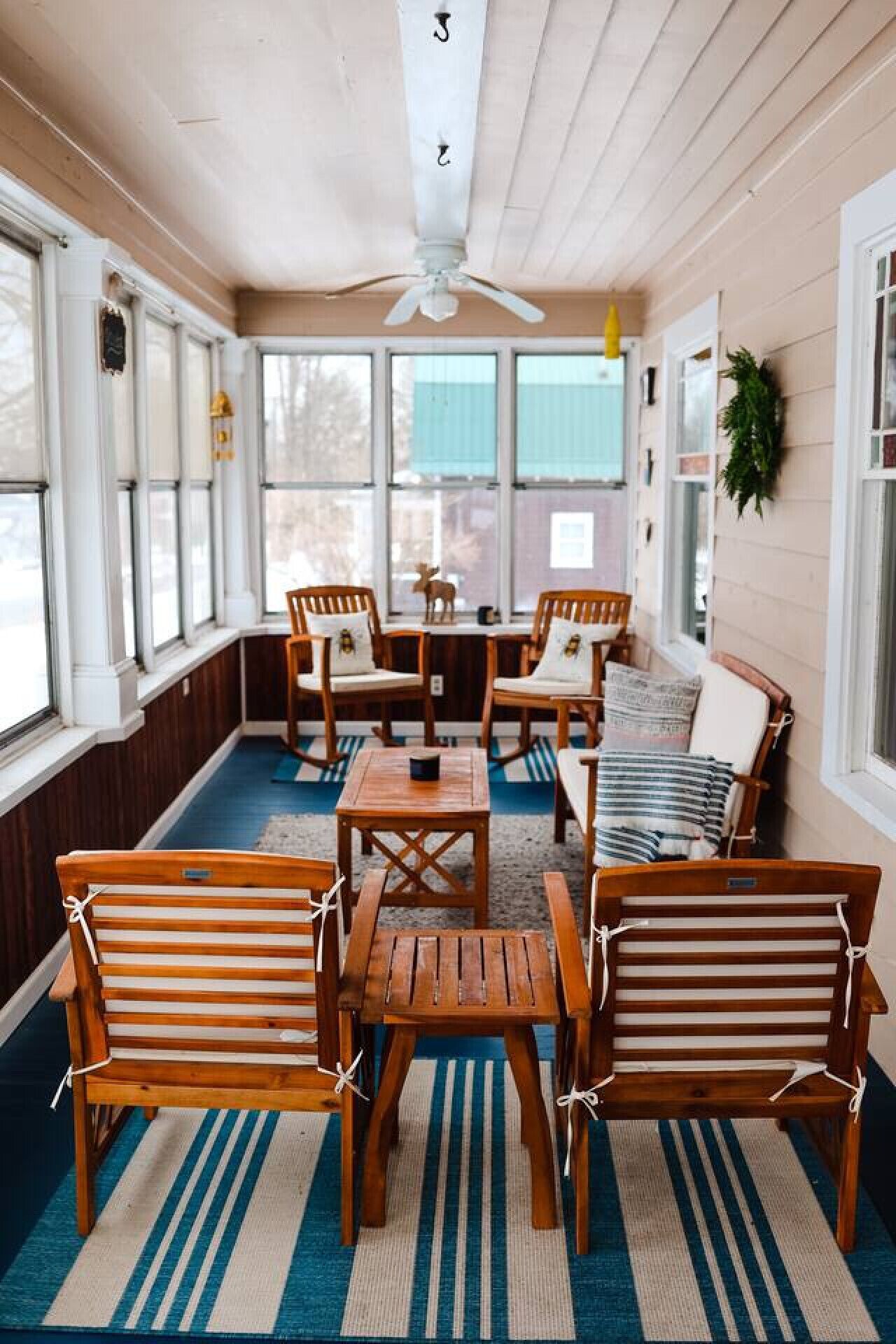 A sunroom with wooden furniture, a ceiling fan, and large windows.