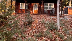 Un chalet rustique doté d’un porche, entouré d’une forêt.