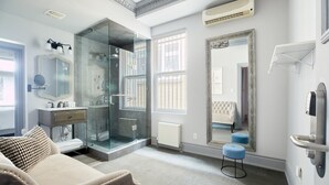 A modern bathroom with a glass shower enclosure, a vanity with a mirror, and a large mirror on the wall. - La TUMU (Toronto)