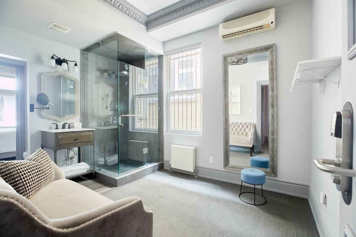 A modern bathroom with a glass shower enclosure, a vanity with a mirror, and a large mirror on the wall.